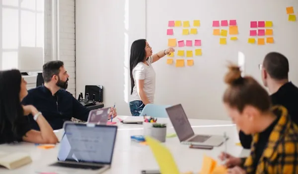 Team meeting with a presenter arranging sticky notes on a whiteboard