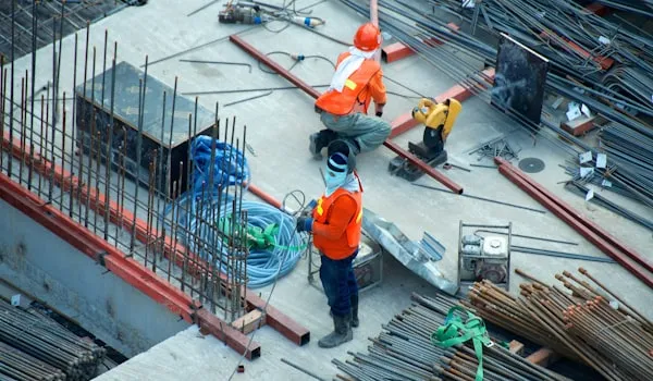 Construction workers in safety vests tying rebar at a job site