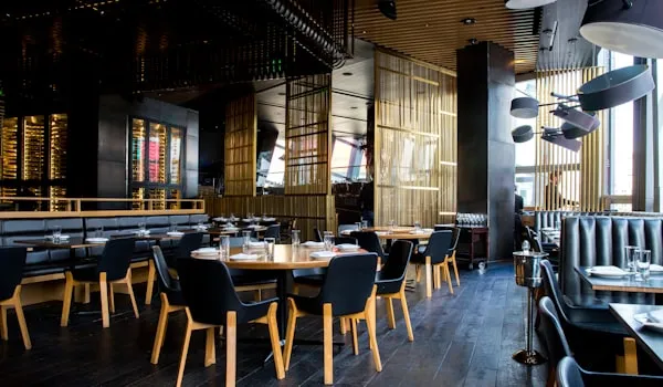 Modern restaurant dining room with dark wood tables and black chairs